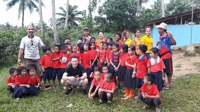 A class of AMSAI School students gathered outdoors with teachers and visitors