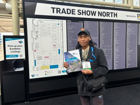 Allan Inocalla holds a conference guide in front of the Trade Show North exhibitor map at an international mining convention