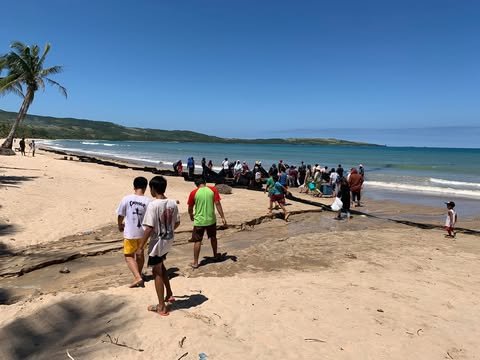Local fishermen and families hauling in a net on Gumaus Beach